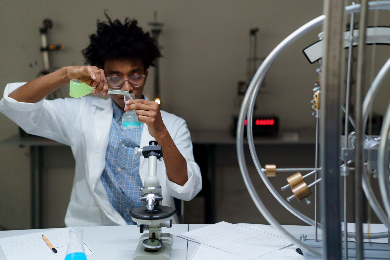 Scientifique en blouse blanche manipulant des flacons près d'un microscope